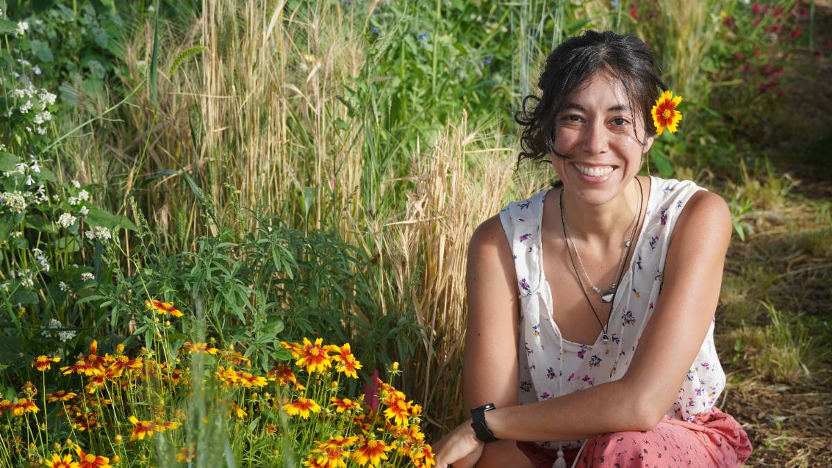 Lina Alegre in the greenhouse with coreopsis, one of the flowers now found in the Rain Garden.