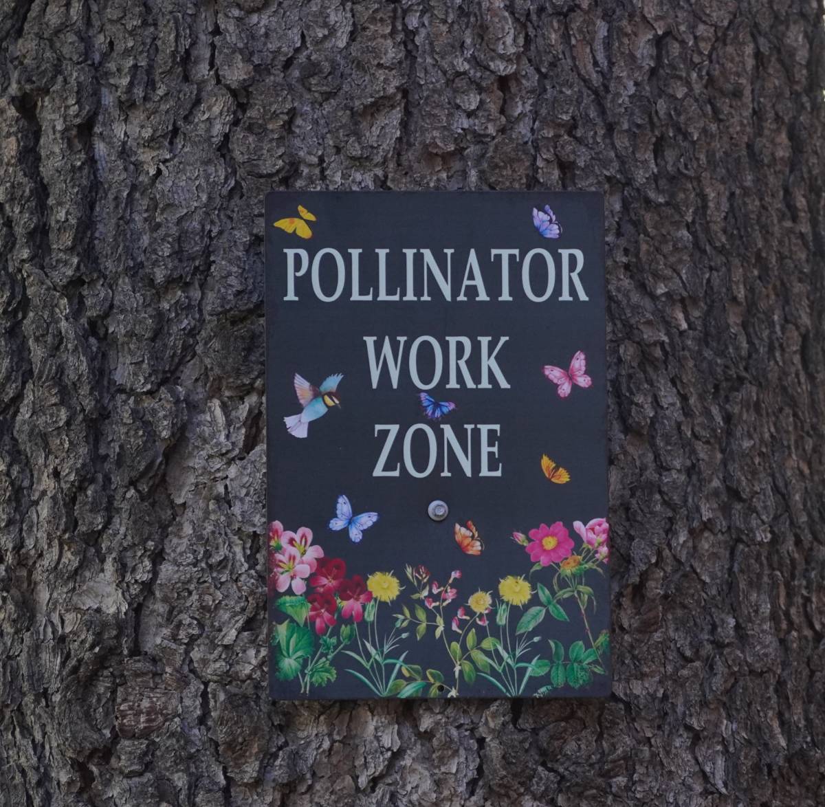 A sign reading "Pollinators at Work"